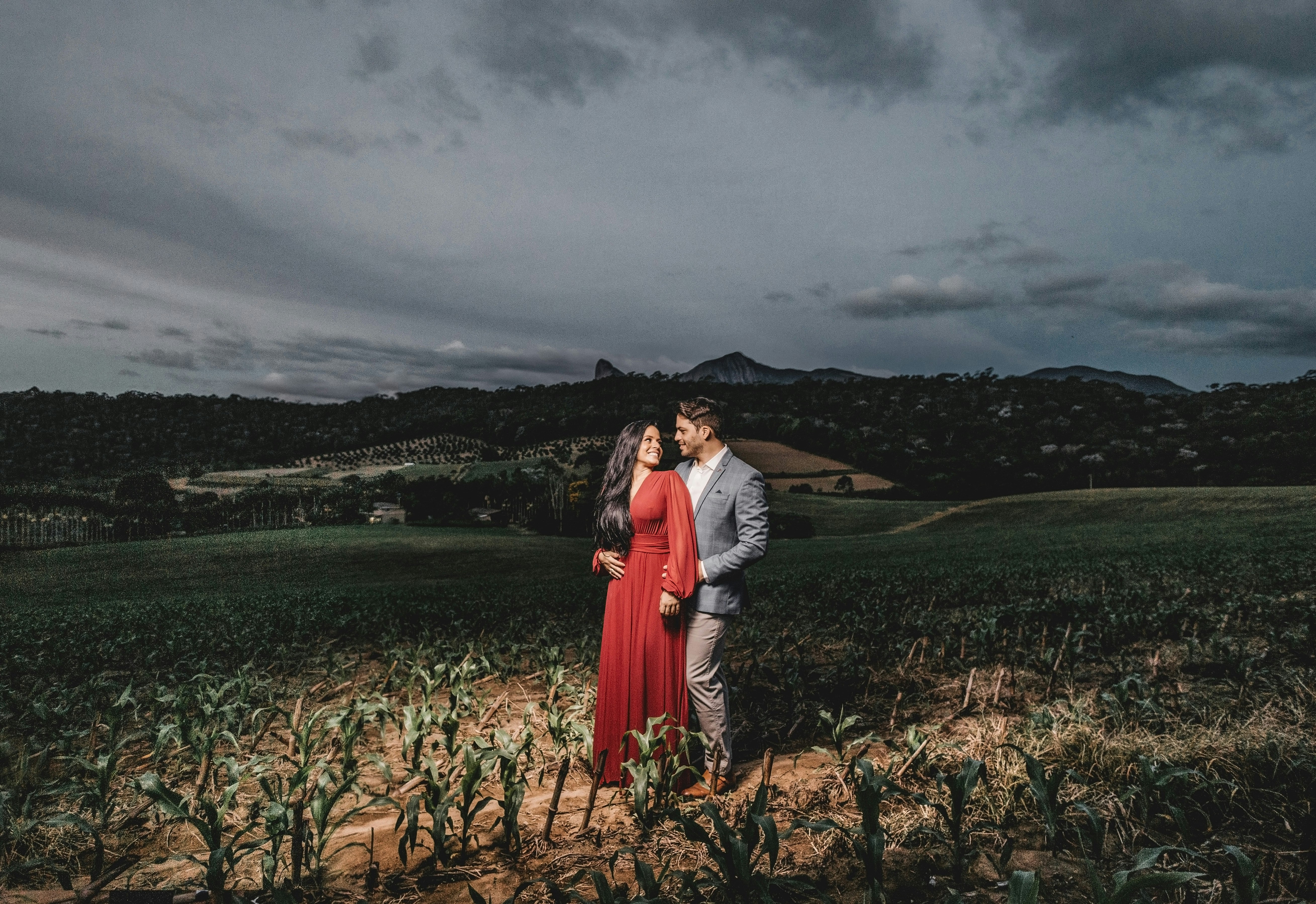 man and woman standing on brown grass field near body of water during daytime